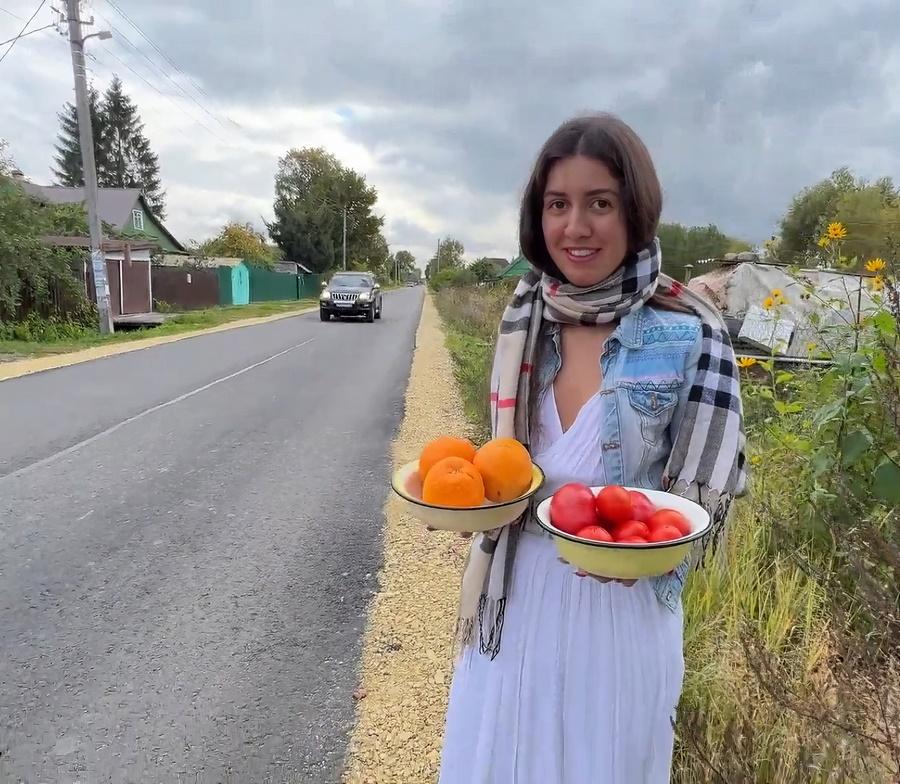 Сельская девушка на трассе торгует фруктами и своей пилоткой